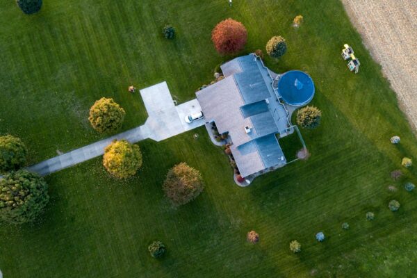 Aerial view of a suburban house with a pool, surrounded by green lawns and autumn trees, in Tipton, Indiana.