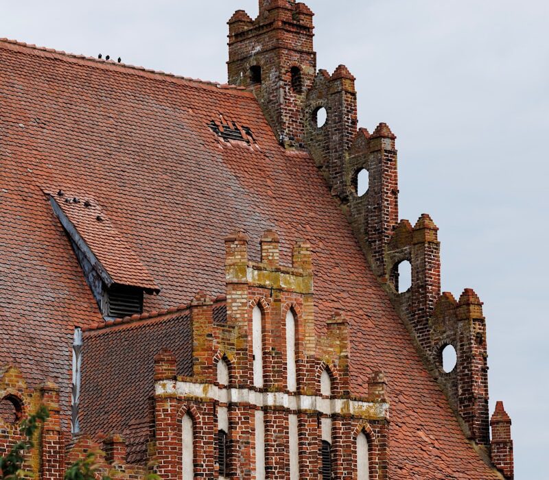 A red brick church roof with unique architecture.